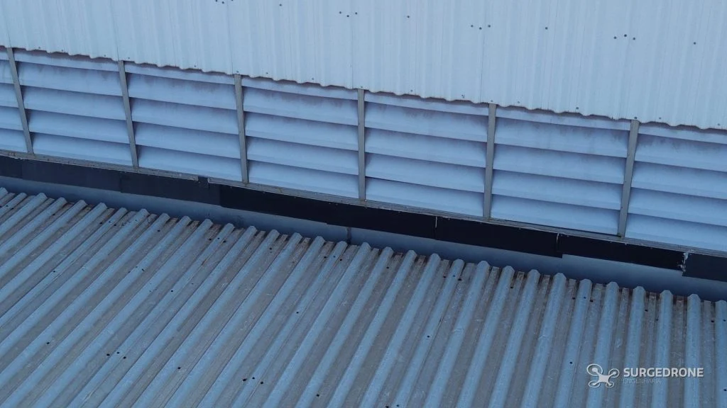 Detalhe de fachada metálica com venezianas registrado por drone