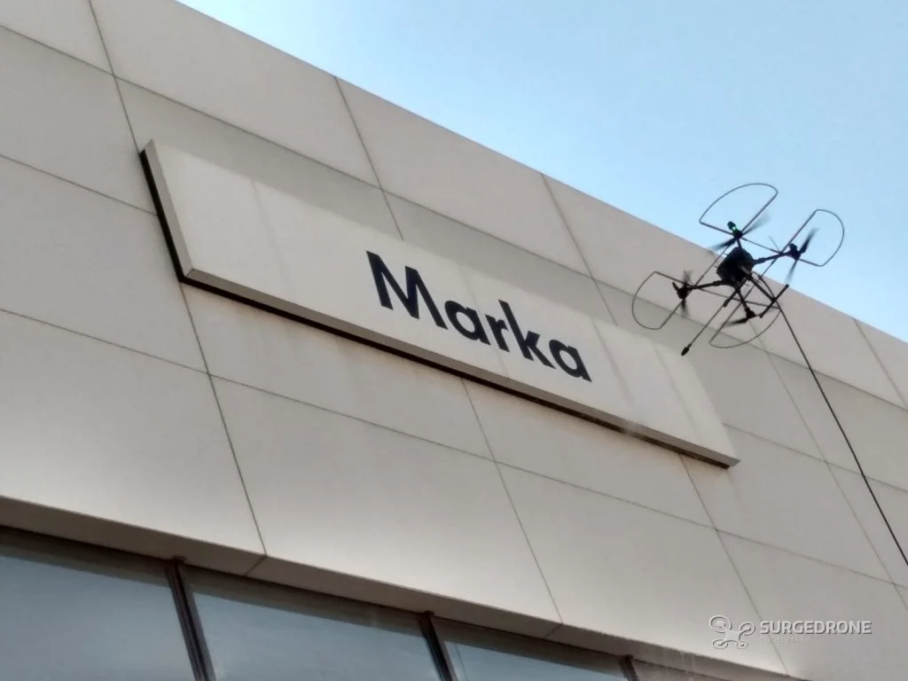 Drone lavando a fachada em ACM de uma concessionária